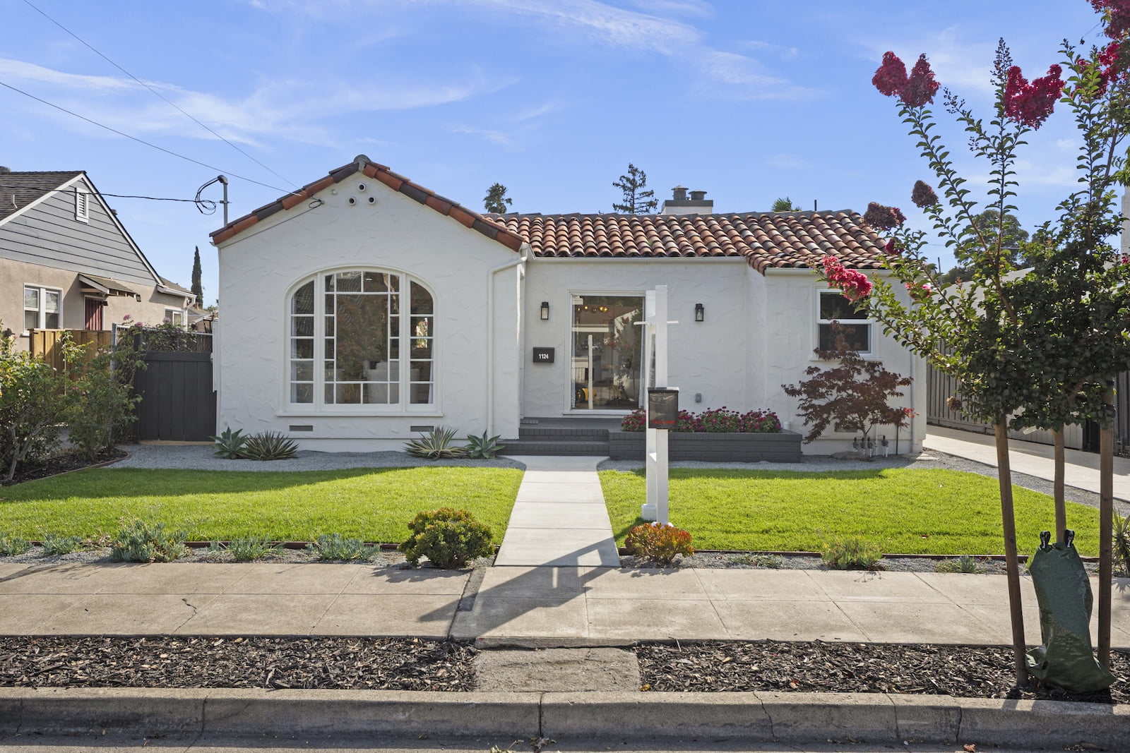 Spanish-Style Home Exterior Painting White stucco home with an arched front window, terracotta tile roof, and landscaped lawn.