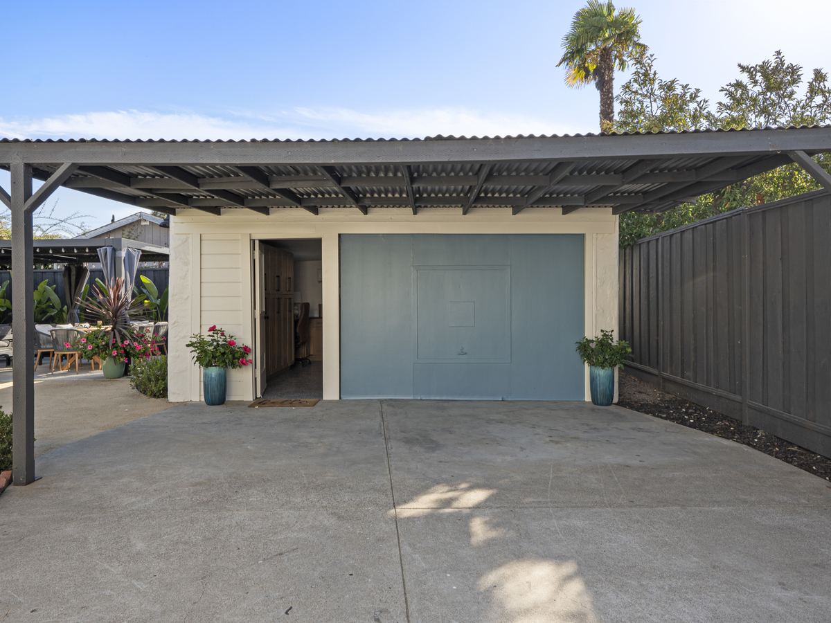 Garage and Carport Exterior Painting Detached garage with a blue door, white exterior, and dark gray carport and fence.